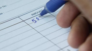  A man writes payment due in a paper form .