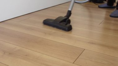Kadın yer tozunu elektrikli süpürgeyle temizliyor.