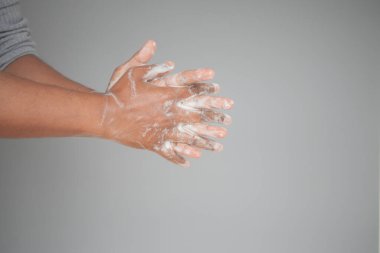 Genç adam ellerini sabunla sıcak suyla yıkıyor..