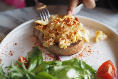 Scrambled eggs on a bread on white plate 
