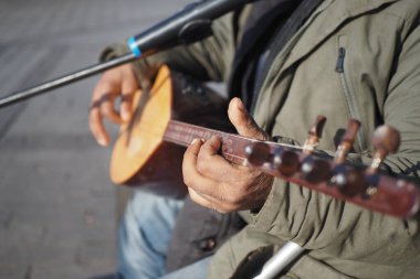 Yetenekli bir sokak müzisyeni güneşin altında geleneksel bir telli çalgı çalıyor ve müzik yeteneğini sergiliyor.