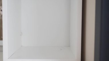 Dekoratif bir feneri beyaz bir rafa yerleştiren bir elin detaylı yakın çekimi., 