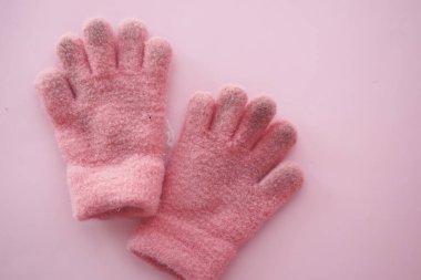 Bir çift yumuşak, rahat, pembe kış eldiveni pastel pembe arka planda serin hava için mükemmel.