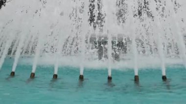 Çeşme jetlerinin yakın plan görüntüsü parlak mavi bir havuza karşı neşeli ve ferahlatıcı bir su ekranı oluşturuyor..