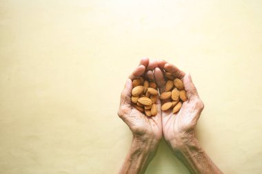 almond nuts on a senior woman hand . clipart
