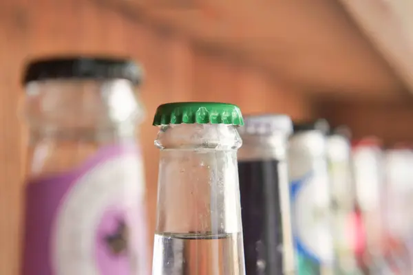 stock image Close-up of assorted vintage beverage bottles featuring colorful caps in a bar or shelf setting.