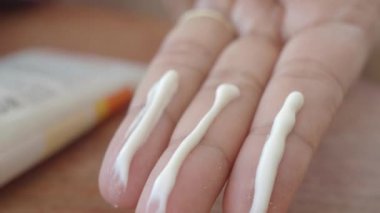Üç parmağına losyon sürmüş bir elin yakından görüntüsü, cilt bakımı için hazır..