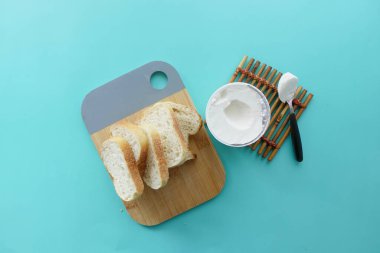 Beyaz arka planda bir dilim ekmek ve krem peynir.