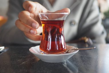 Geleneksel Türk çayını beyaz masada içen kadın 