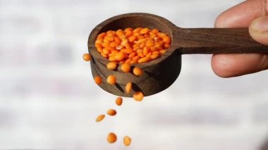 Tahta kaşıktan yavaş yavaş mercimek dökülüyor. .