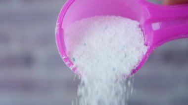 Plastik kaşıktan çamaşır tozu dökülüyor. ,