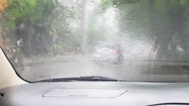 Arabanın ön camını kaplayan yağmur damlacıkları ıslak camların arasından yolu göremez..