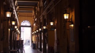 Klasik sokak lambaları ve dekoratif mimari detaylarla donuk ışıklandırılmış tarihi bir iç kapı geçidi.