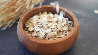 Kavrulmuş yulafların ağır çekimde ahşap bir kasede dökülmesi. .