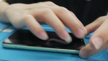 Atölye masasındaki akıllı telefondan bakım ve onarım yapan teknisyenlerin yakın çekimi..