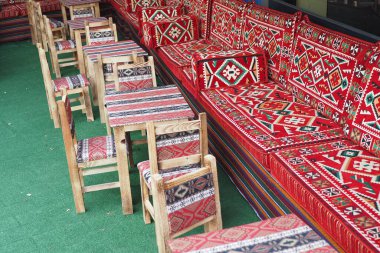 Geleneksel bir kafede açık hava koltukları desenli yastıklar, kırsal ahşap masa ve sandalyeler.