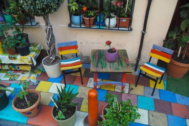 Açık hava kafe canlı, renkli bitkiler, sandalyeler ve güzel bir mozaik zemin ile süslenmiş.