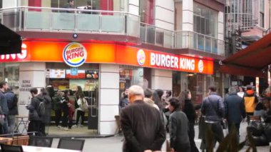 İnsanlar kalabalık bir kentsel alanda kalabalık bir Burger King 'in önünden geçip toplanıyorlar..