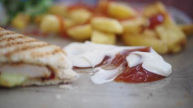 Izgara sandviç, patates kızartması ve kremalı sos ve ketçap da dahil olmak üzere sosun yakın çekim görüntüsü..