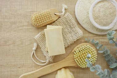 Tahta bir yüzey üzerinde sabun, vücut fırçası, lif ve okaliptüs içeren doğal spa seti..