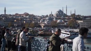 Istanbuls Galata Köprüsü: alacakaranlıkta balıkçılar, camiler ve minarelerle gökyüzü. Simgesel şehir manzarası.