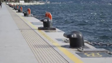 Dalgalı suları ve uzak kıyı şeridi olan kıyı rıhtımı boyunca uzanan kalın yelkenlilerin yakın görüntüsü