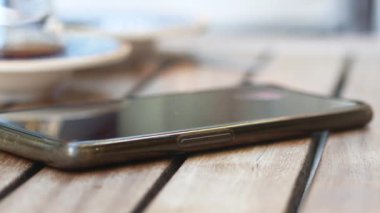 Adam el masadan akıllı telefon alıyor.