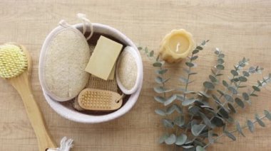 Tahta bir yüzey üzerinde sabun, vücut fırçası, lif ve okaliptüs içeren doğal spa seti..