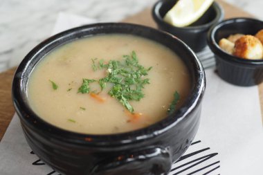 Maydanozla süslenmiş siyah bir kasede doyurucu çorbanın yakın görüntüsü. Rahatlatıcı yemek temaları için mükemmel.