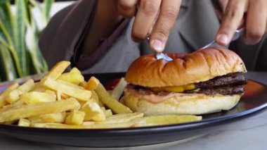Kadın çatal ve bıçakla çizburger kesiyor. .