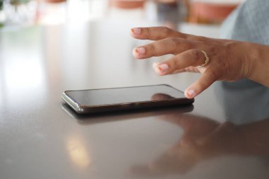 Adam el masadan akıllı telefon alıyor.