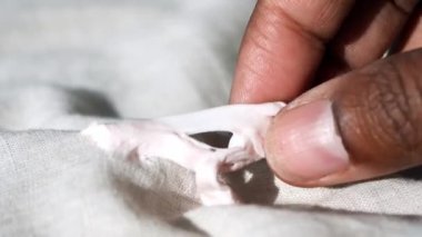 Koyu renk kumaştan parmaklarıyla sıkışan sakızı çıkarmak..