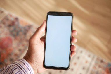 boş ekran ve ev dekorasyonlu akıllı telefonu masada tutmak .