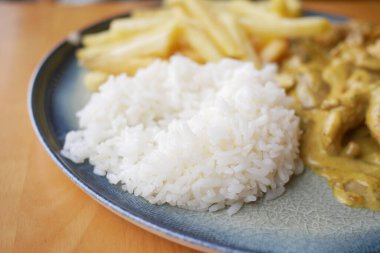 Beyaz pirinç ve patates kızartması bir tabakta çatalla, yemek düzeninde, yemek için hazır.