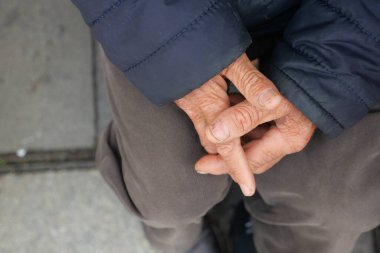 Yaşlıların ellerinin birbirine yapışık olduğu, yaş ve deneyimin resmedildiği detaylı bir bakış açısı.