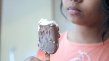 Çocuk fındıklı çikolatalı dondurmanın tadını çıkarıyor, tatlı bir ziyafetin tadını çıkarıyor.