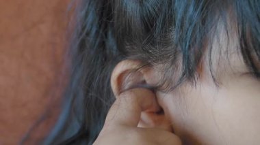  Kulak ağrısı çeken bir çocuk acı veren kulağına dokunuyor. 