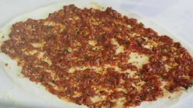 Ekmek hamuruna baharatlı et ekleyerek, pişirmeye hazır bir elin yakın çekimi..