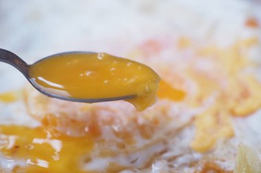 Makro bir kaşık dolusu yumurta sarısı pişmiş yumurta beyazı, zengin dokuları yakalıyor.