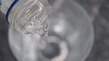 Yakın plan bir perspektif suyu şişeden bardağa akarken yakalar, bu da hidrasyon kavramını sembolize eder.