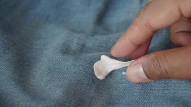 Koyu renk kumaştan parmaklarıyla sıkışan sakızı çıkarmak..