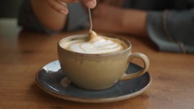 İnsan, kaşıkla kahve karıştırır.