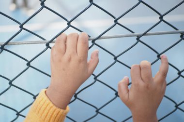 Çitlere tutunan çocukların elleri neşe ve merak dolu.