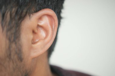 Sarı arka planı olan genç bir adamın kulağını kapat.