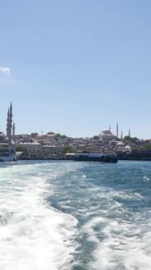 Bir tekne engin okyanus boyunca seyahat eder, sakin mavi sularda ardında köpüklü bir iz bırakır.