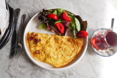 Salata ve çayla servis edilen sade yumurtalı omletin üst görüntüsü. .
