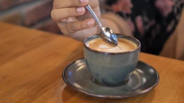 İnsan, kaşıkla kahve karıştırır.