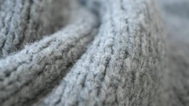 Gri örülmüş kumaşın detaylı bir makro görüntüsü, sıcaklığı ve samimiyeti yansıtan karmaşık dokusunu gözler önüne seriyor.