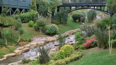 Yumuşak bir akarsu, canlı çiçekler ve yeşil bitki örtüsünden oluşan sakin bir park..