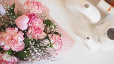 İçinde pembe karanfiller, bebek nefesi ve özel durumlar için mükemmel kalp şeklinde bir süs bulunan çarpıcı bir buket..